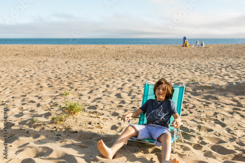 Boy relaxing on folding chair at the beach photo
