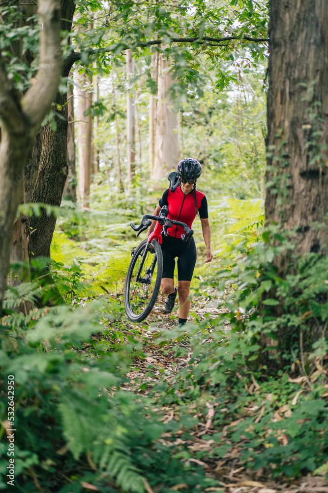 Young sportswoman carrying bike and walking in woods Young sportswoman carrying bike and walking in woods