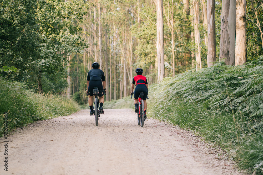 Faceless cyclists riding on road in nature Faceless cyclists riding on road in nature