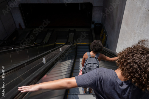 Siblings descend escalator photo