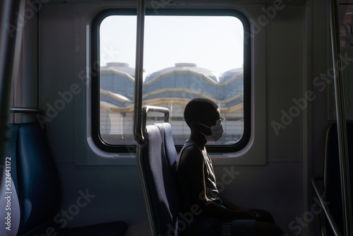 Profile of boy in mask alone on train photo