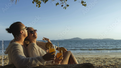 Cute loving couple in white dress, sunglasses, relax in hugging and drinking cocktail Pina Colada. Concept sea beach resting tropical tourism summer holidays wedding love family vacations