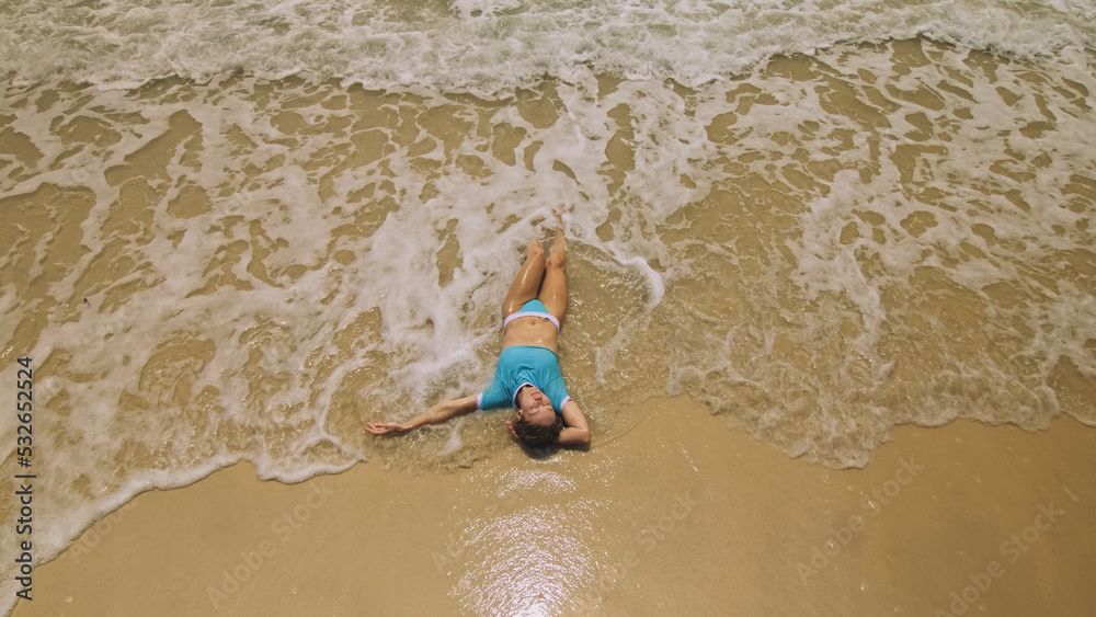 Crazy madwoman daring funny woman lying on shallow water sea. Top view ...