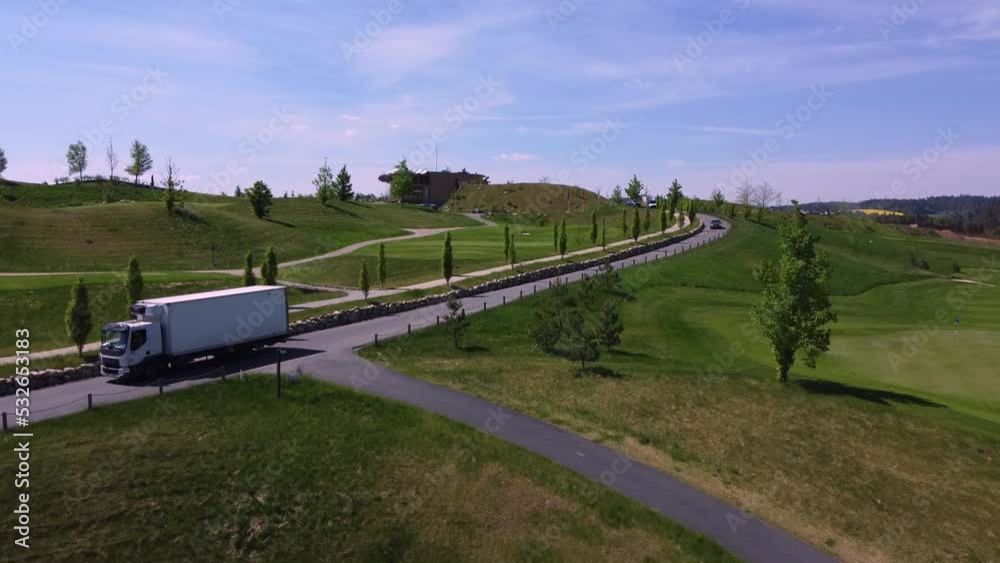 Golf course and road with driving truck and car, aerial drone view, sunny day, green grass, Kacov in Czech Republic Golf course and road with driving truck and car, aerial drone view, sunny day, green grass, Kacov in Czech Republic