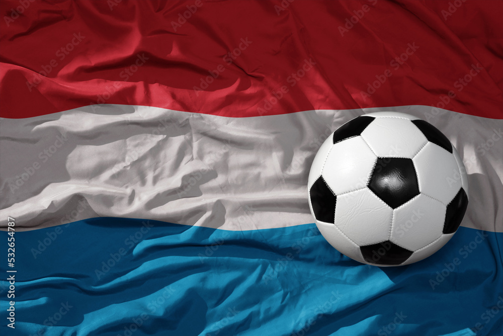 Naklejka premium vintage football ball on the waveing national flag of luxembourg background. 3D illustration