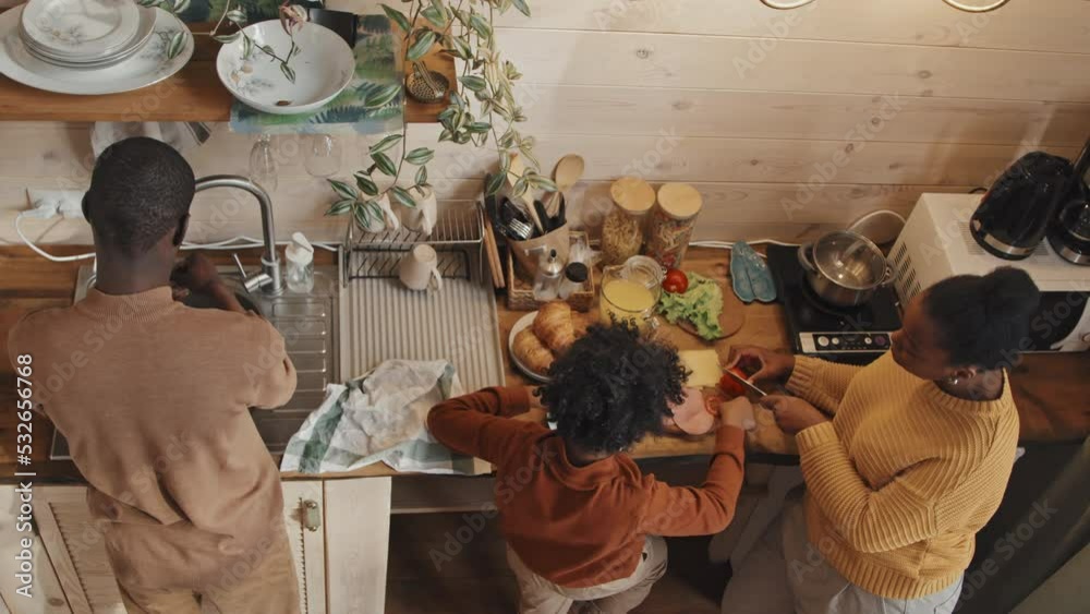From above view of modern African American family of three standing in country house kitchen cooking meal together