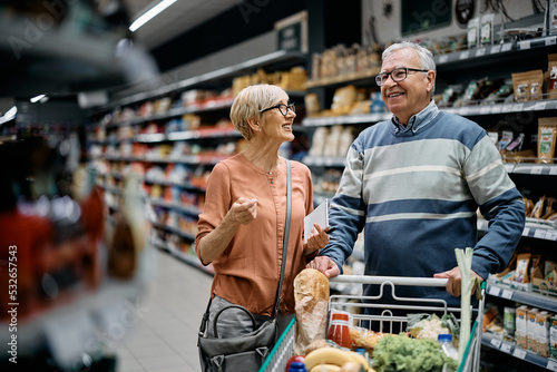Happy senior couple talks while shopping in supermarket.