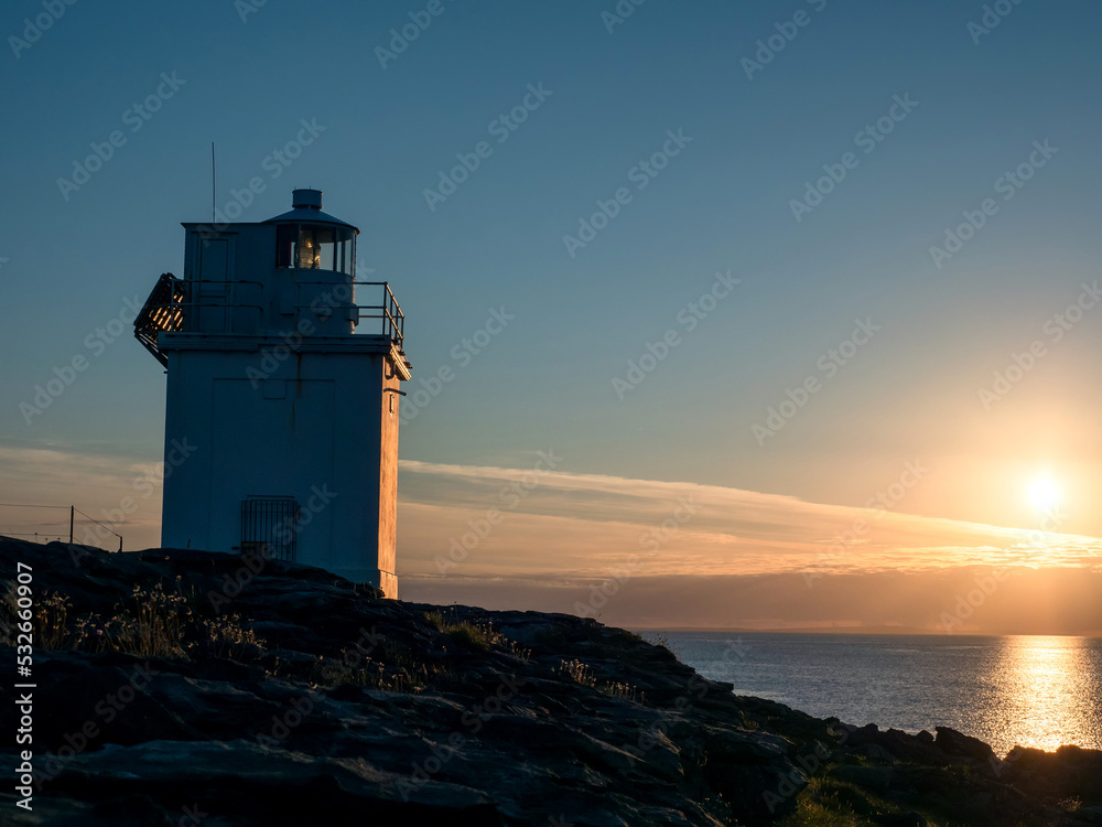 Silhouette of Black Head Lighthouse in Burren, Ireland. Galway bay in the background. Blue cloudy sunset sky. Famous landmark on Wild Atlantic Way tourist route. Calm nature scene.