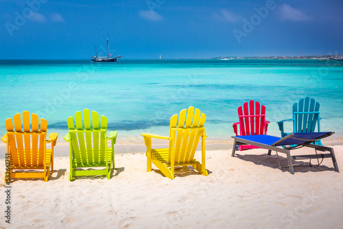 Billede på lærred Colorful chairs in Aruba, turquoise caribbean beach with ship, Dutch Antilles