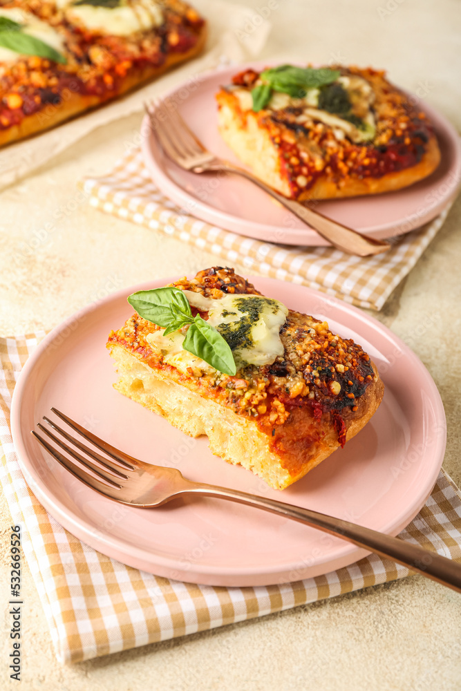 Plates of tasty Italian pie with mozzarella and pesto sauce on light table Plates of tasty Italian pie with mozzarella and pesto sauce on light table