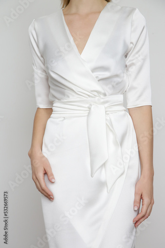 Serie of studio photos of attractive young woman wearing elegant white silk satin dress.