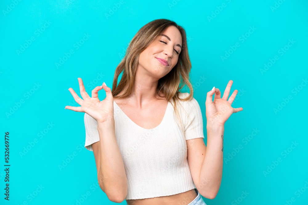 Fototapeta premium Young caucasian woman isolated on blue background in zen pose