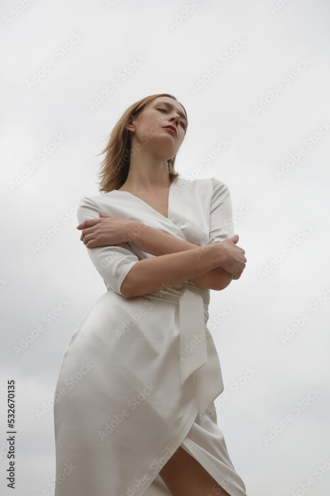 Serie of studio photos of attractive young woman wearing elegant white silk satin dress. Serie of studio photos of attractive young woman wearing elegant white silk satin dress.