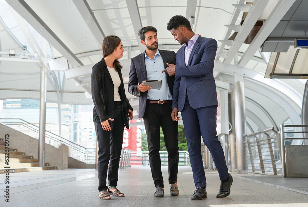 group of young multiracial business people chatting and looking at tablet online work while walking outside group of young multiracial business people chatting and looking at tablet online work while walking outside