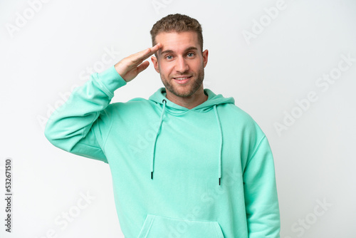 Young handsome caucasian man isolated on white background saluting with hand with happy expression © luismolinero