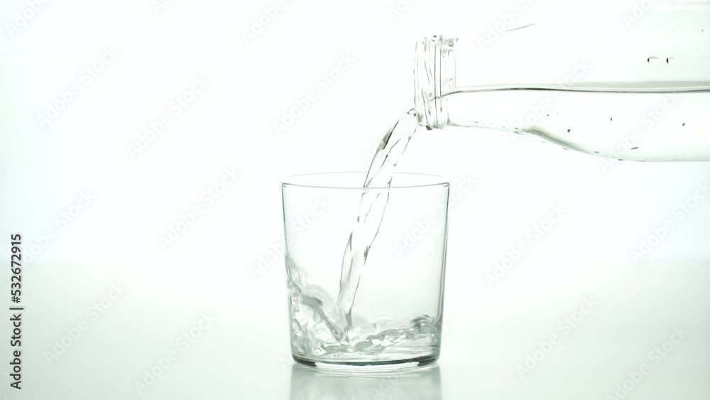 Detail of an unrecognizable man's hand pouring water into a crystal glass on a white background. Detail of an unrecognizable man's hand pouring water into a crystal glass on a white background.