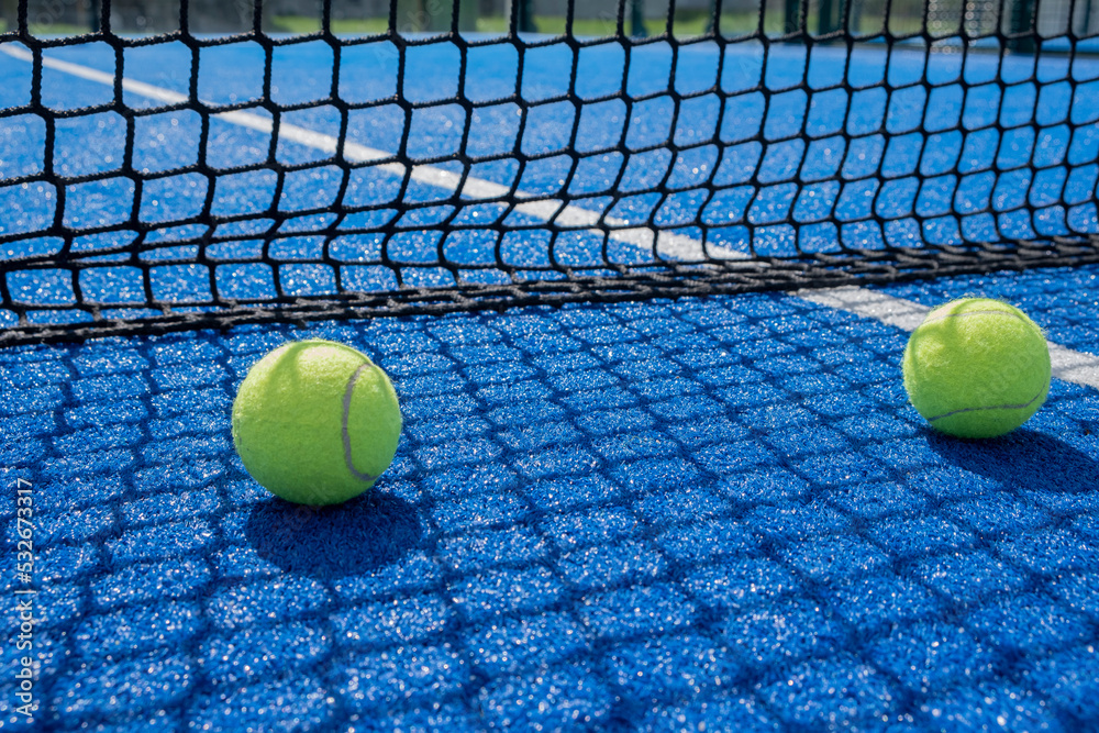 two balls near the net of a paddle tennis court