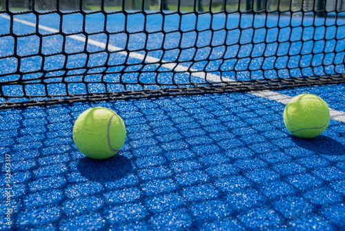 two balls near the net of a paddle tennis court © Vic
