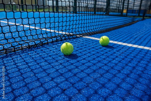 two balls near the net of a blue paddle tennis court © Vic