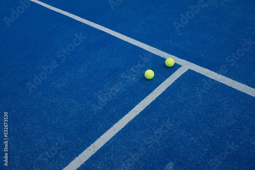 two balls next to the side of a blue paddle tennis court © Vic