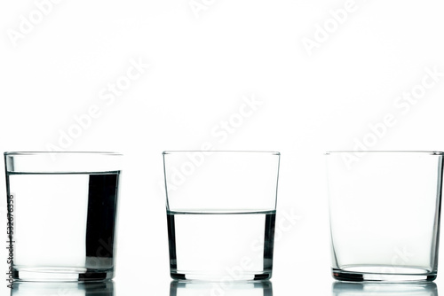 Foto Three crystal glasses, one full of liquid, one half-full and one empty - concept