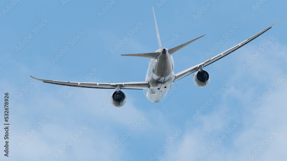 Avion comercial despegado, tomando altura con cielo azul con algunas nubes, con el fuselaje brilloso