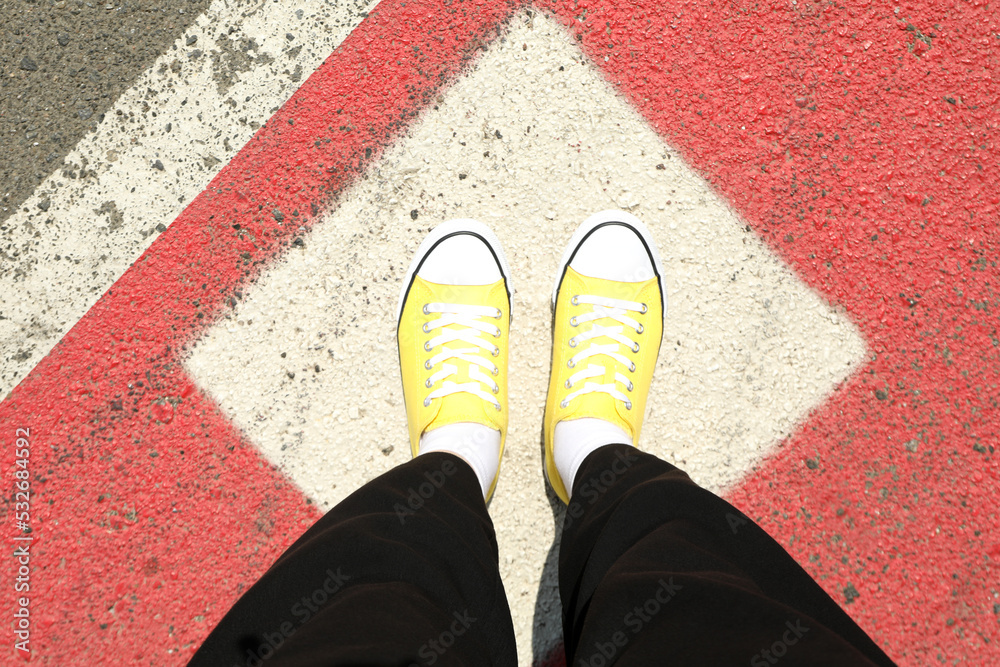 Female legs in yellow sneakers outdoor in sunny day, top view Female legs in yellow sneakers outdoor in sunny day, top view