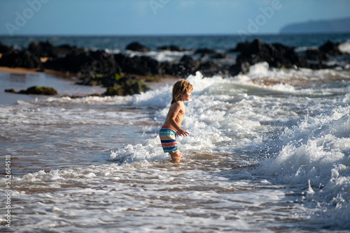 Fototapeta Naklejka Na Ścianę i Meble -  Boy kid jumping in sea waves. Jump by water sea splashes. Summer kids vacation.