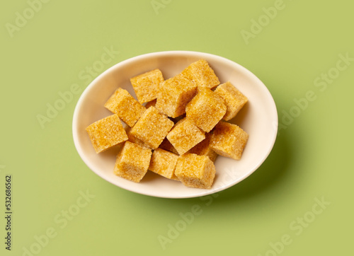 Brown cane sugar cubes in a white saucer. Top view.