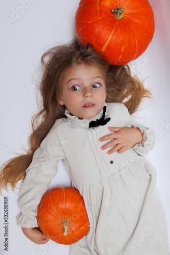 Halloween portrait of a little girl . Little child with pumpkins. White background.  photo