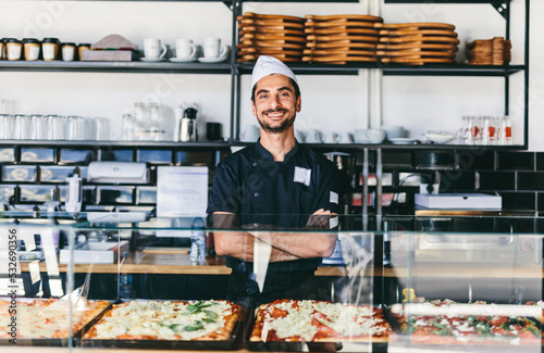 Italian chef or pizzaiolo with sicilian pizza in restaurant