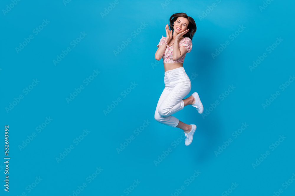 Photo of cute adorable inspired pretty lady jump arm cheekbones wear stylish outfit empty space isolated on blue color background
