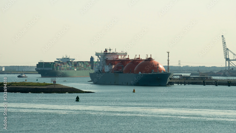 LNG carrier during cargo operations and large container vessel underway behind while leaving the European port