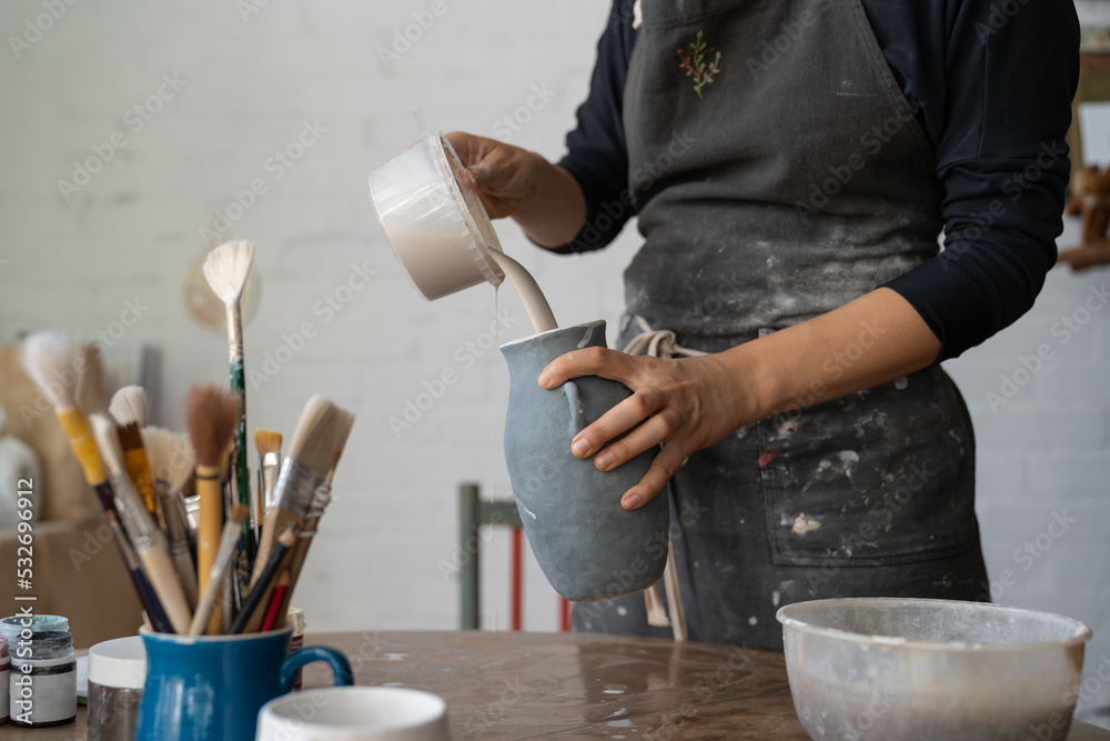 Ταπετσαρία Craftsmaster wearing dirty apron pours liquid from plastic bowl into grey vase