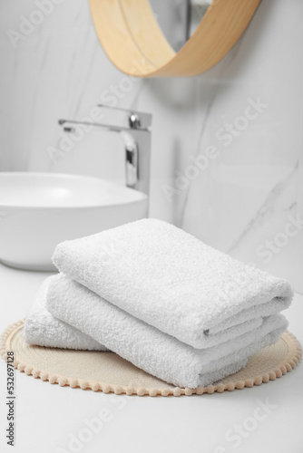Folded bath towels on white table in bathroom