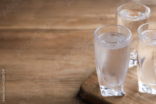 Vodka in shot glasses on wooden table. Space for text