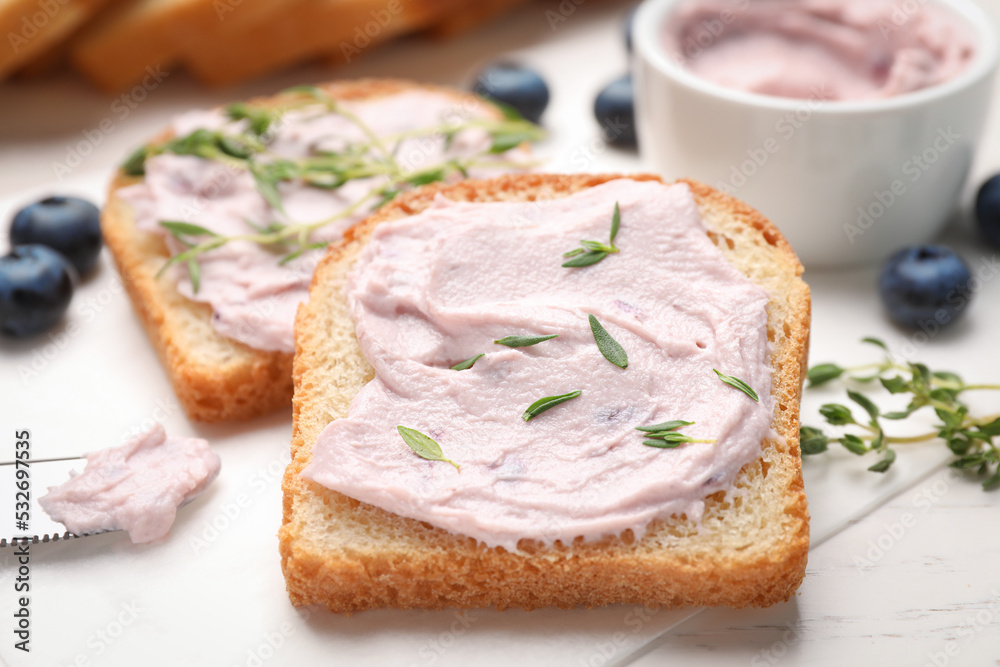Tasty sandwiches with cream cheese, thyme and blueberries on white wooden table, closeup