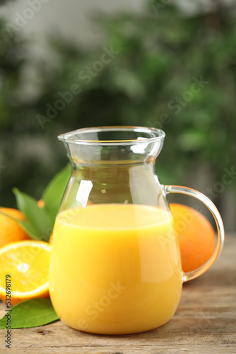 Jug of orange juice and fresh fruits on wooden table