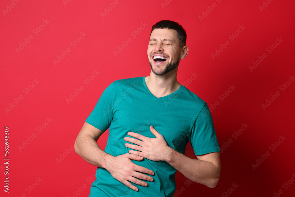 Handsome man laughing on red background. Funny joke Handsome man laughing on red background. Funny joke