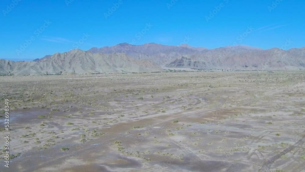 View of a drone ascending over plain land showing a mountain in the background View of a drone ascending over plain land showing a mountain in the background