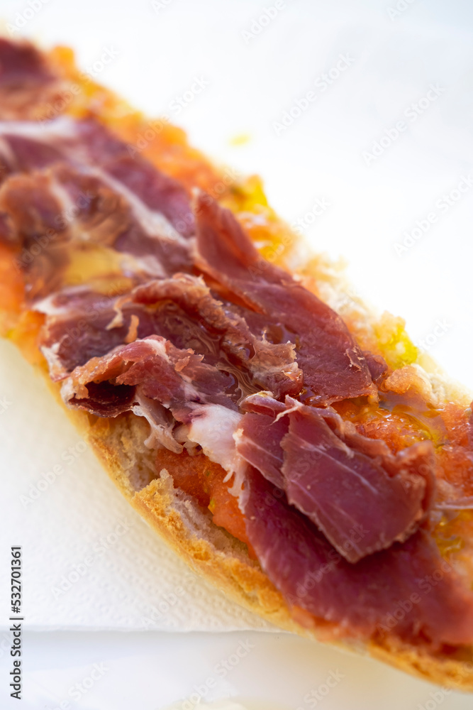 Breakfast toast of cured ham with the bread served on a white plate on a white table. Close-up