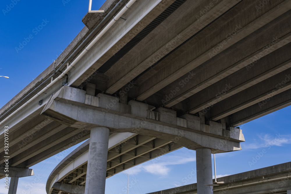 View Underneath a Large Bridge Highway on a Sunny Day with Blue Sky View Underneath a Large Bridge Highway on a Sunny Day with Blue Sky