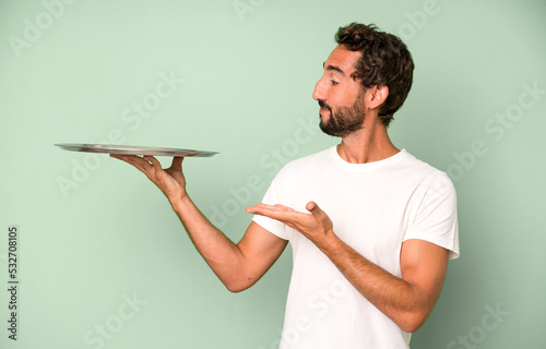 young crazy bearded and expressive man holding an empty steel tray photo