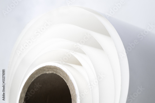 White polygraph paper on a cardboard core. A bundle of leftover paper in a printing house. Material for the printing industry. Selective focus