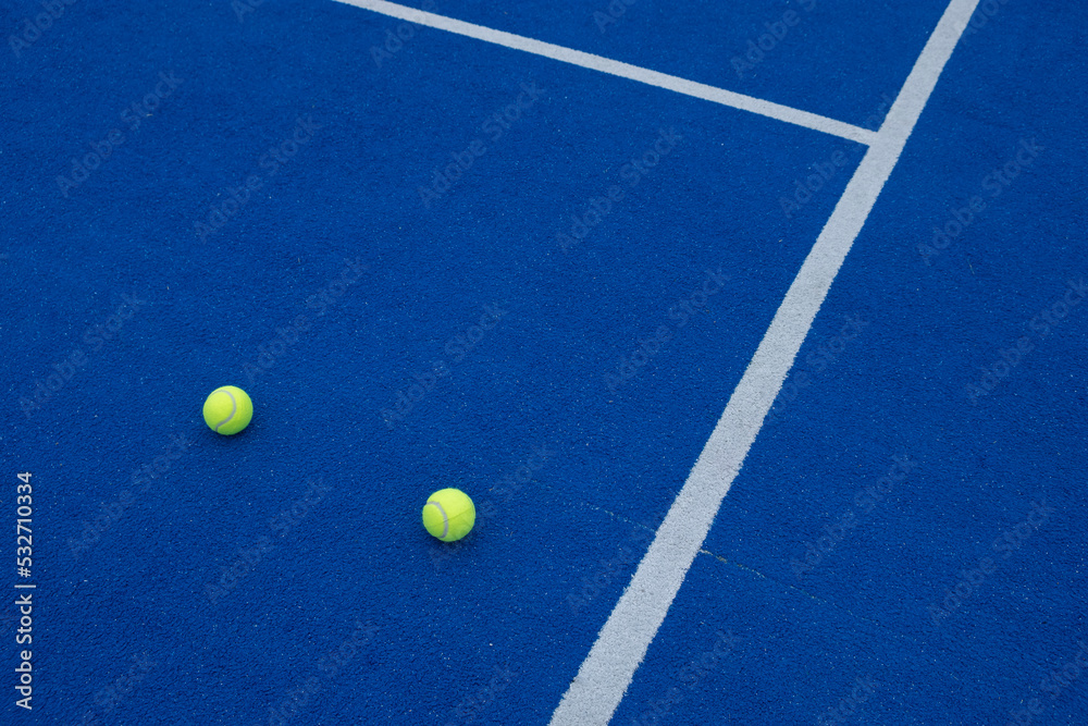 Blue paddle tennis court, two balls by the line
