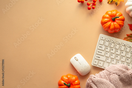 Autumn office workspace. Keyboard, laptop, notebok with autumn clothes and fall decorations - pumpkin, leaves and other. Fall flat lay. photo