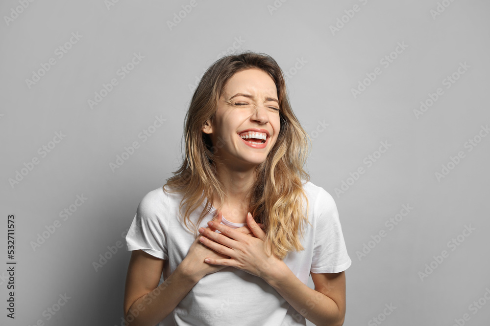 Cheerful young woman laughing on grey background Cheerful young woman laughing on grey background