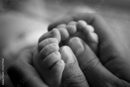 The feet of a newborn baby in the hands of the mother. Parent holding in the hands feet of newborn baby. Happy Family concept. Selective focus