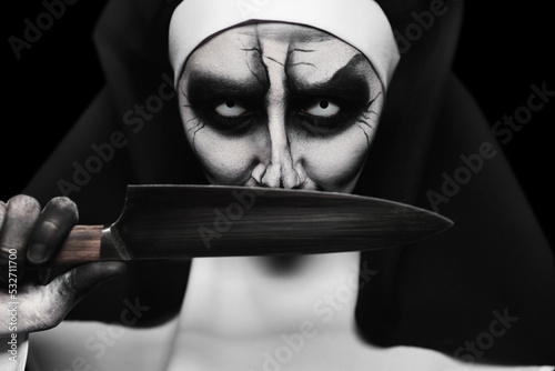 Scary devilish nun with knife on black background, closeup. Halloween party look