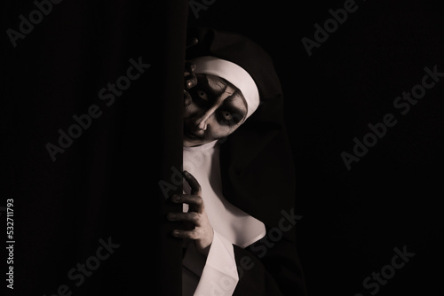 Scary devilish nun hiding on black background  space for text. Halloween party look